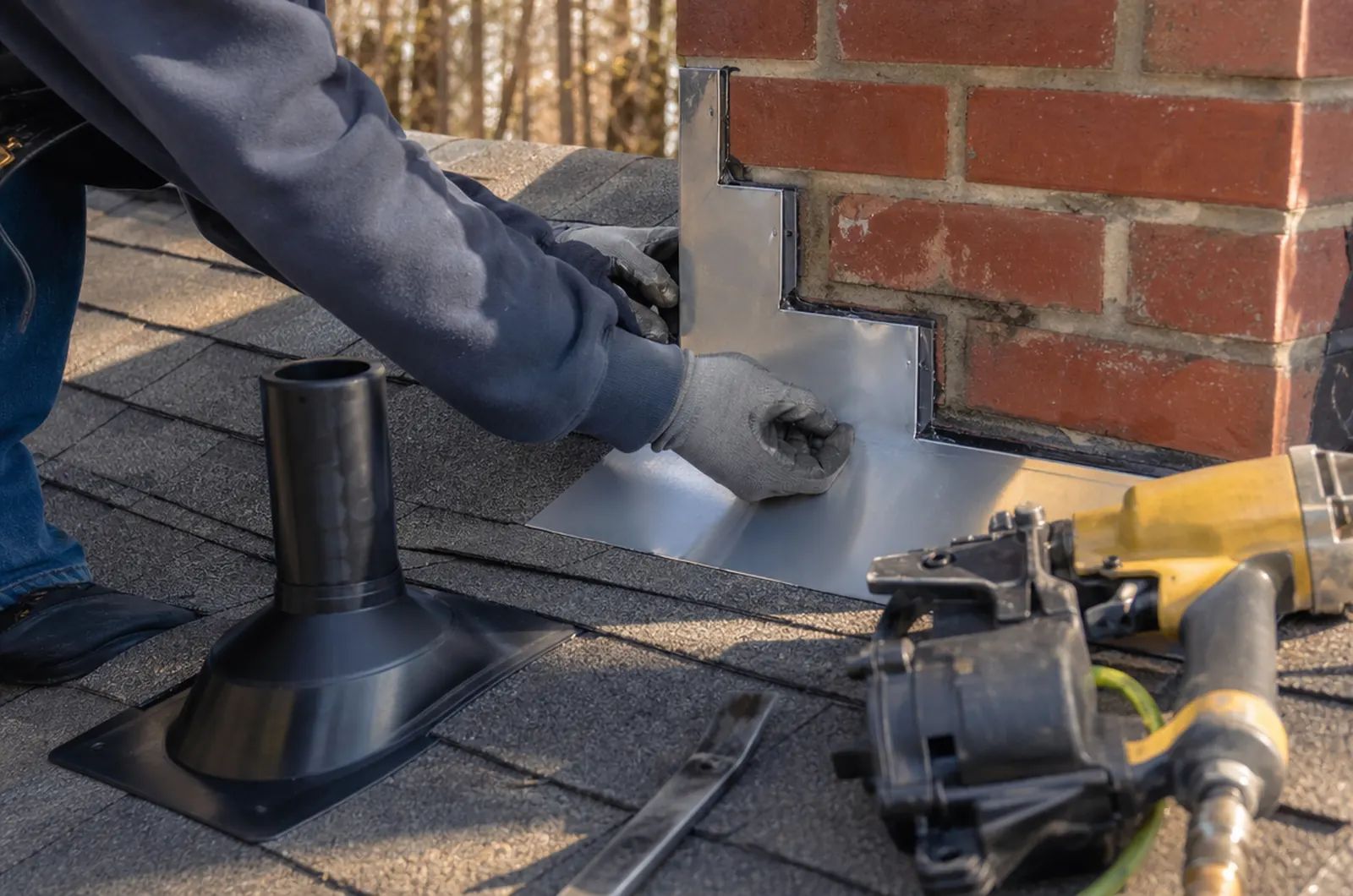 Roof repair in Charleston, SC: roofer installing chimney step flashing and a new pipe boot during a roof repair